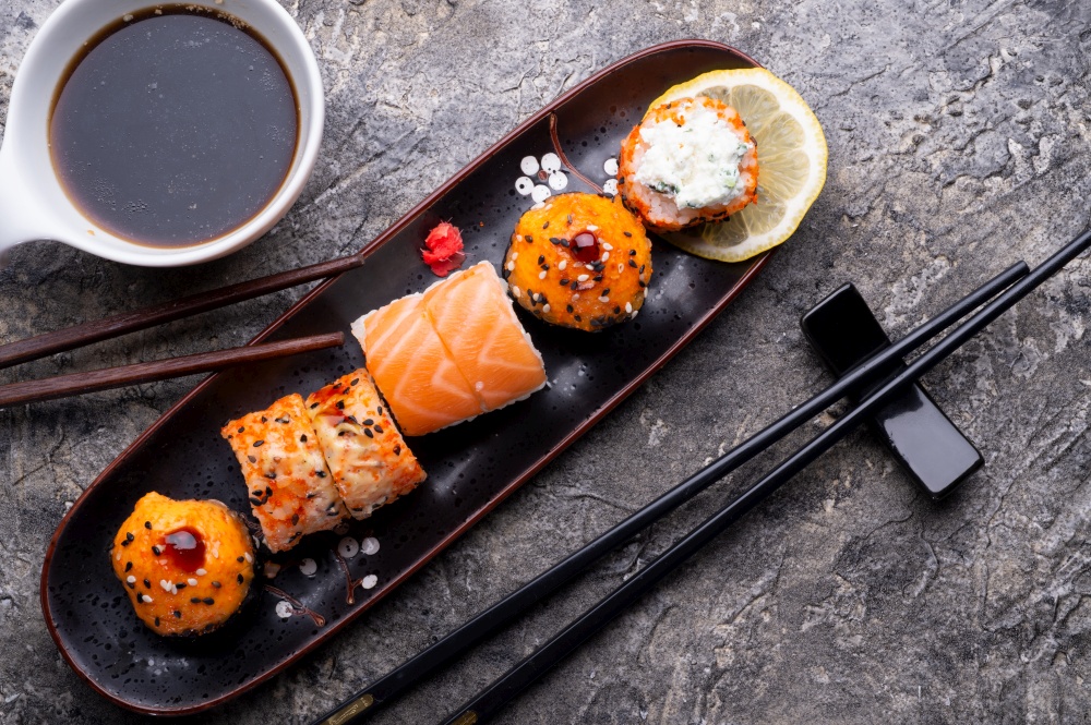 sushi roll set served  at black tray at grey table. flat lay