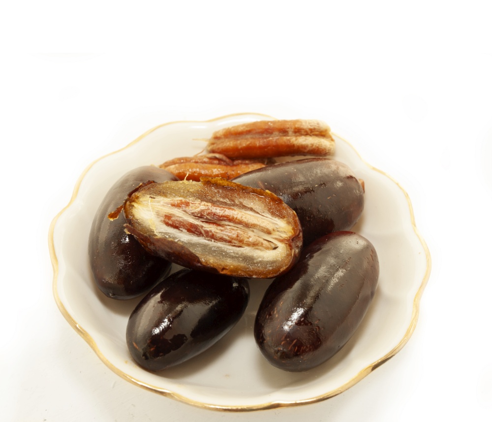 Fresh big dates  in sauce dish isolated on white background. close up