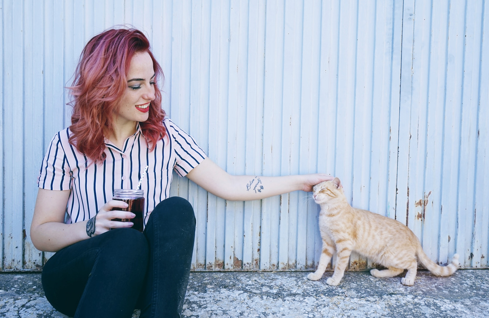 Young redhead woman playing with her cat outdoors