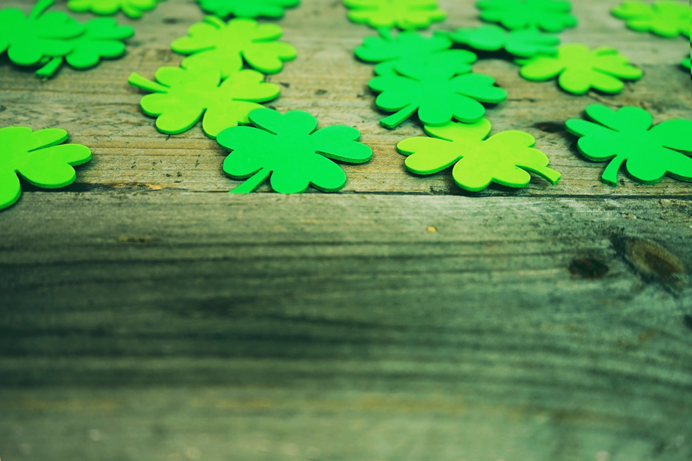 Beautiful close-up of many irish shamrocks, feast clovers, in a row that remind luck or Saint Patrick&rsquo;s Day and wooden tables as background