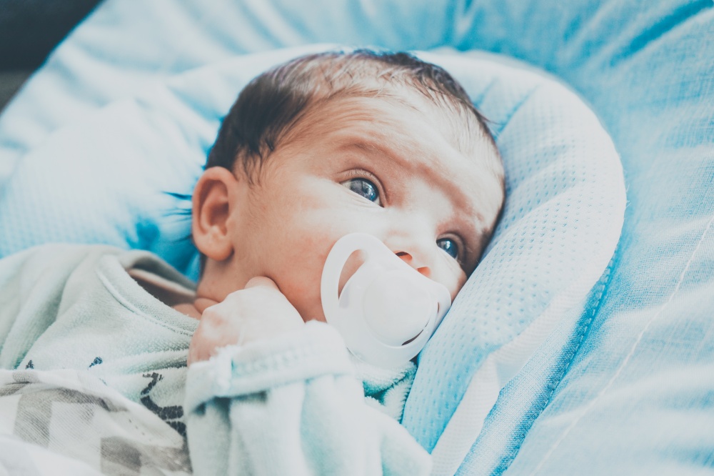 Newborn girl using a pacifier