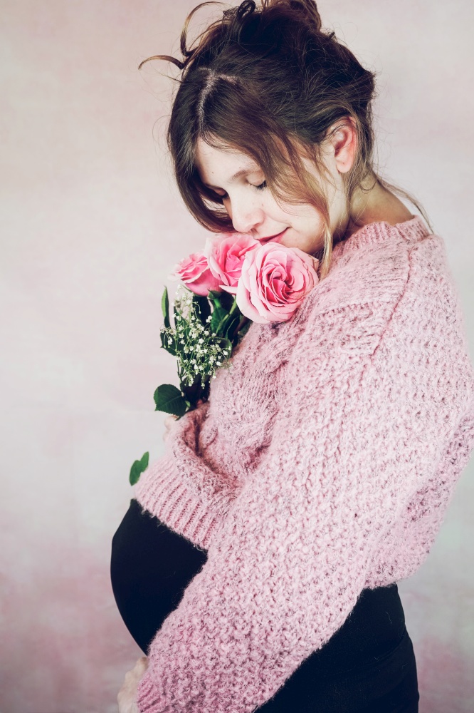 Young pregnant woman holding a bouquet of roses