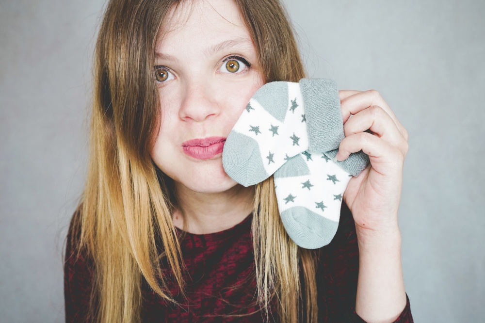 Young pregnant woman holding baby socks