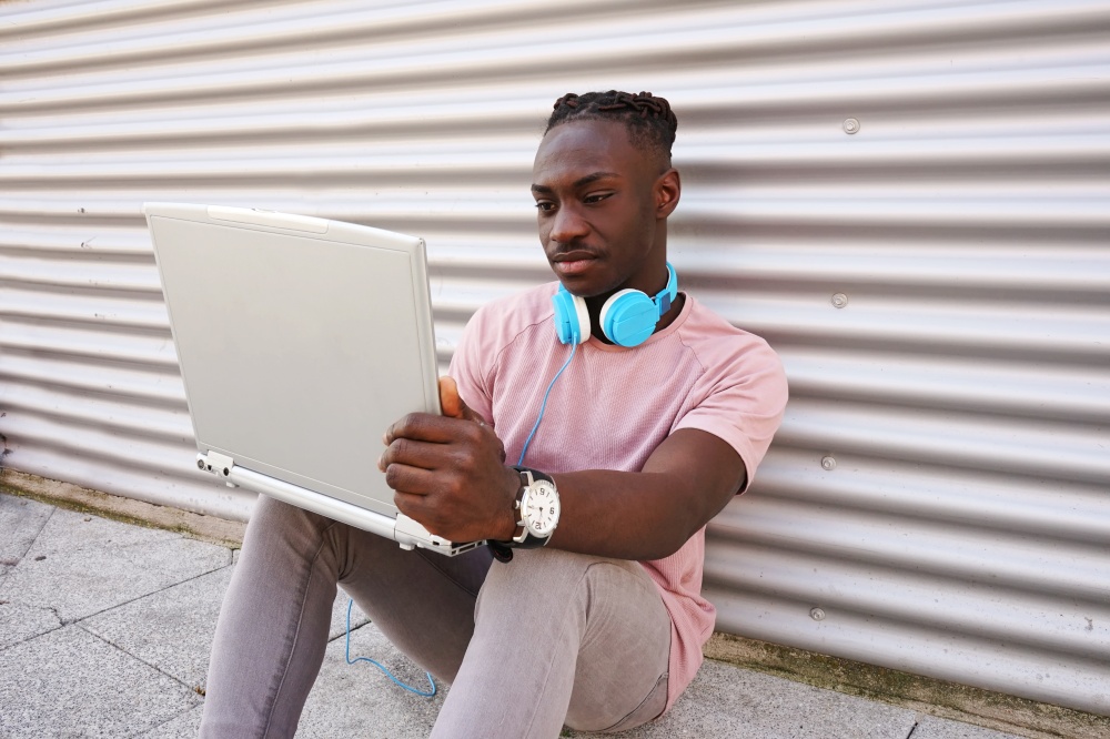 Young man working with his laptop while listen to music