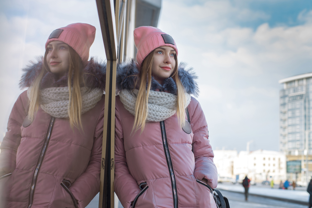 A girl in a pink jacket walks in the winter in the city