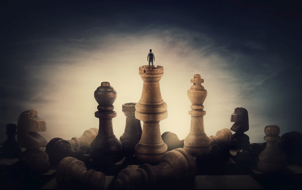 Chess player achieving success. Surreal and conceptual scene of a tiny person standing on the top of chessboard among huge chess pieces. Overcoming obstacles, victory and business leadership metaphor
