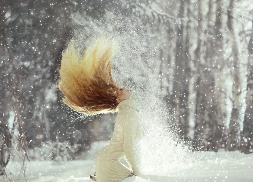 woman shakes her head by the hair of snow
