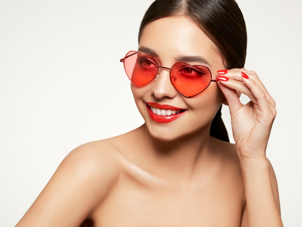 Portrait of beautiful young woman in sunglasses in the shape of hearts. Valentine&rsquo;s Day. Symbol of love