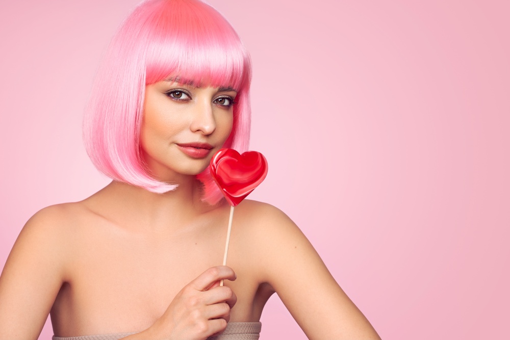 Beauty model portrait with pink hair. Bob short Haircut. Beautiful glamorous girl with a heart-shaped lollipop