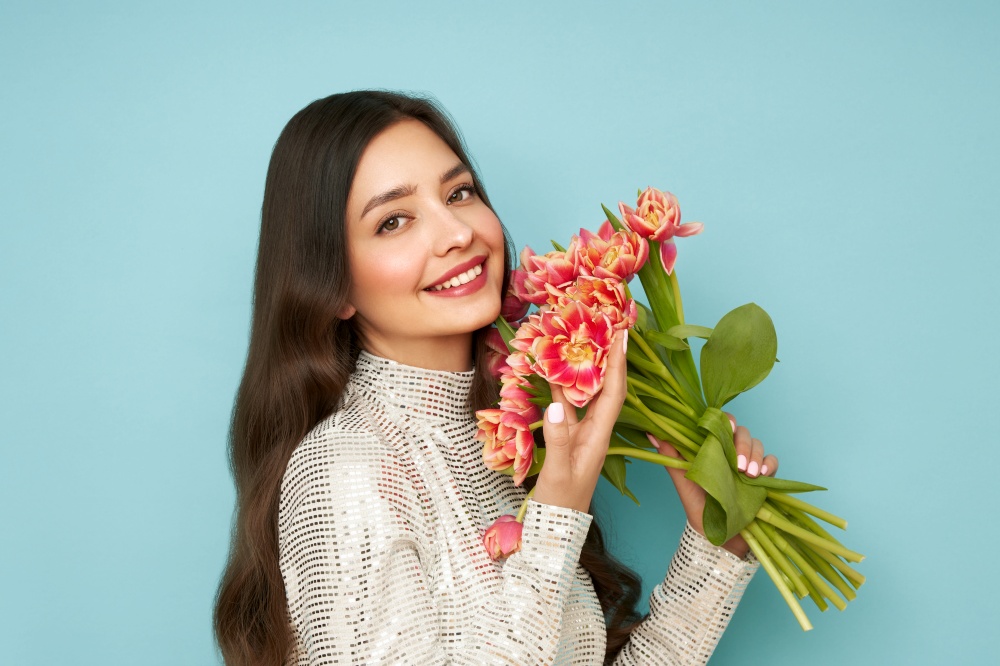 Happy beauty woman with pink tulip bouquet on blue background. 8th of March celebration