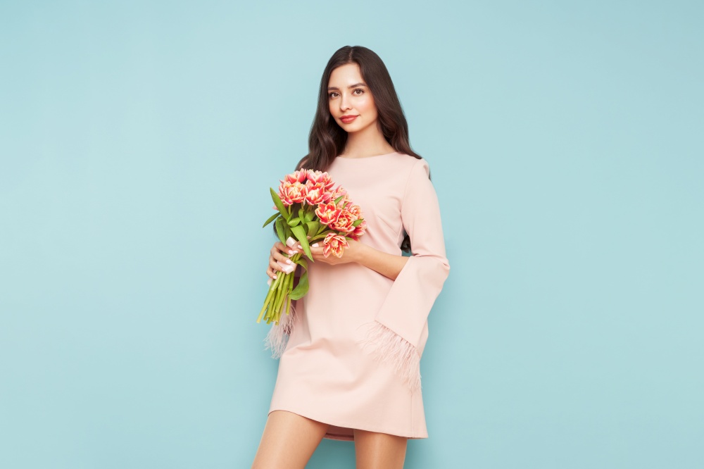 Happy beauty woman with pink tulip bouquet on light blue background. 8th of March celebration