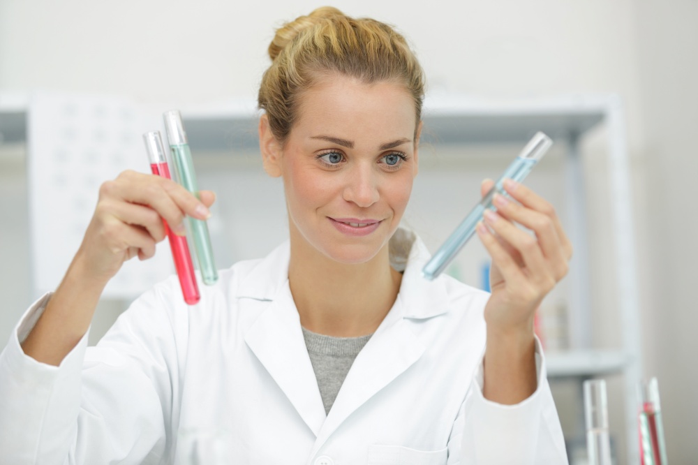 happy female medical worker compares test tubes