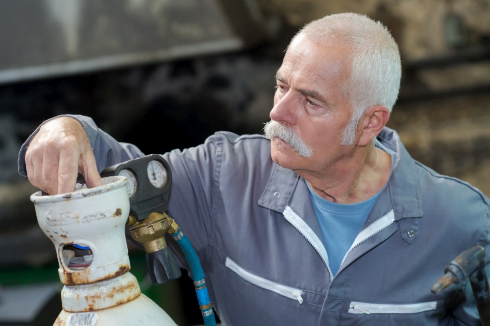 senior welder setting gas bottle before welding