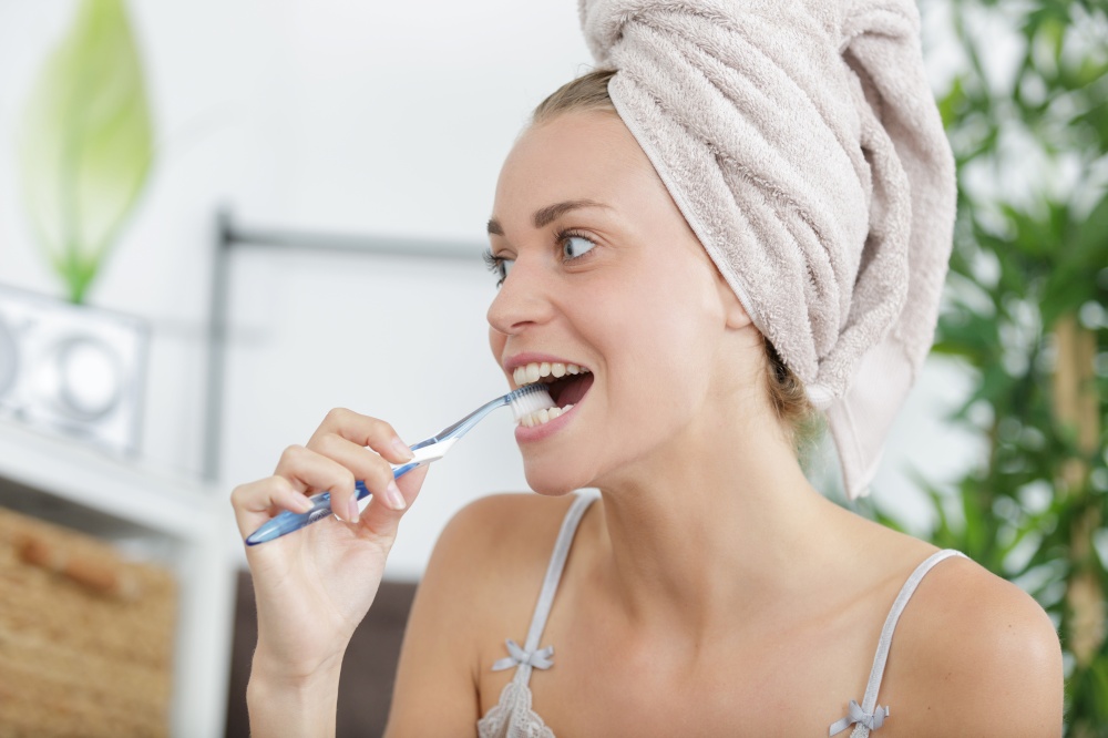 beautiful woman girl in towel covering her head with toothbrush