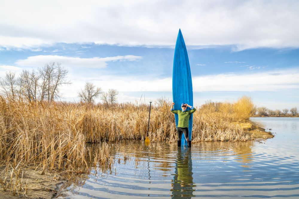 early spring stand up paddling, senior male with his paddleboard on lake in Colorado