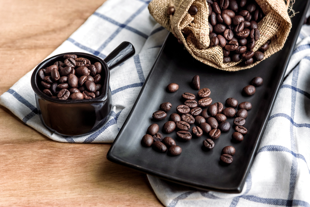 coffee beans in cup and bag on wooden background, selective focus