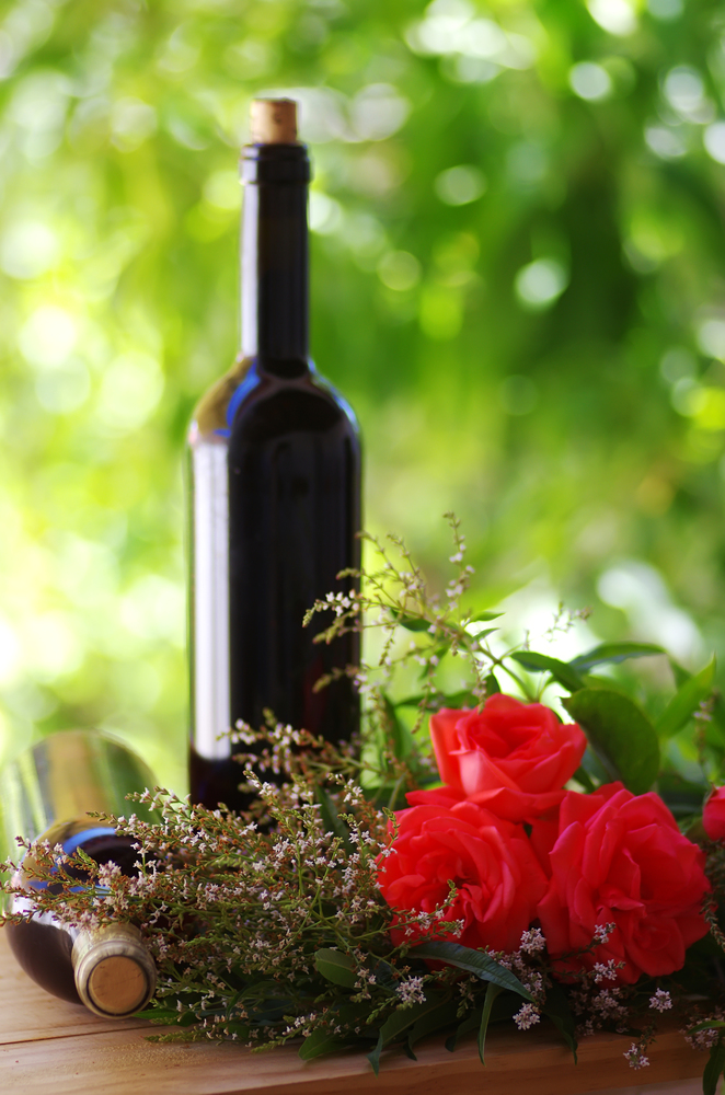 Roses with red wine bottles on wooden table