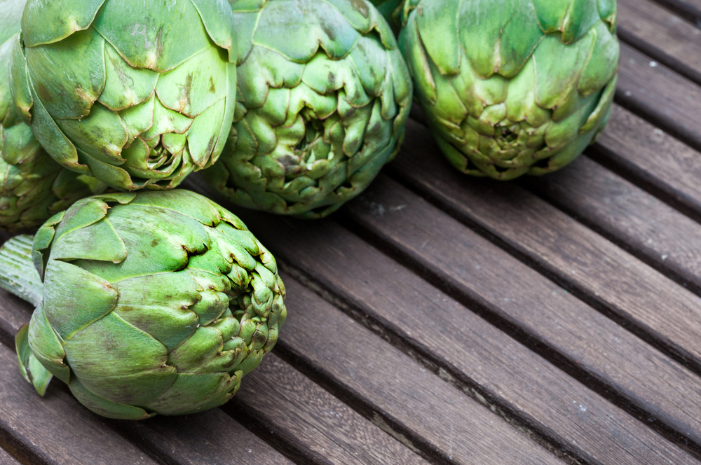 Artichokes on wooden table. - Image