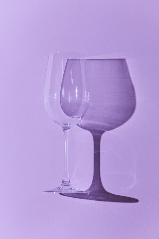 Wineglass isolated on purple background with reflection of shadow. Flat lay. Wineglass isolated on purple background