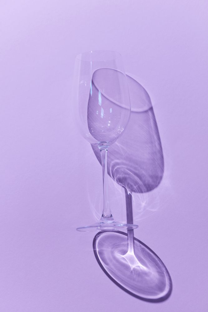 Wine glass in a snifter casting a shadow over a purple background together with the shadows. Wine Glass with shadow on purple background