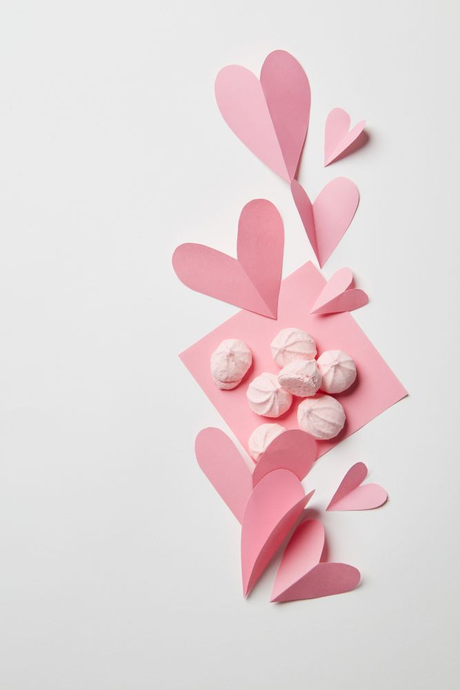 beautiful paper hearts and pink meringues in the corner of a white background. concept valentine card