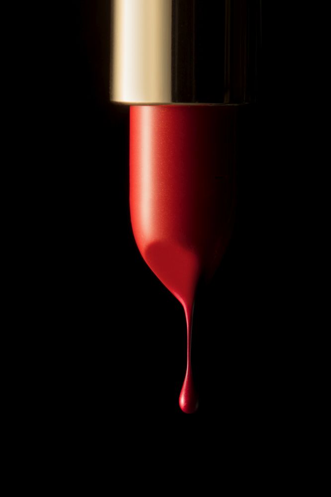 Red melting lipstick isolated on black background. Red lipstick on black background