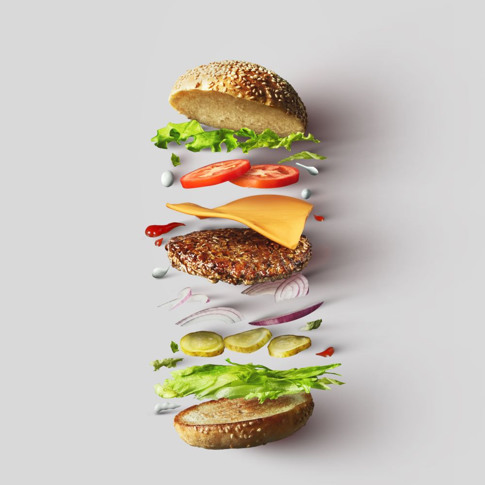 Top view of burger ingredients represented against white background. Hamburger or sandwich with cheese, tomato, beef, etc. Top view. Burger ingredients against white background