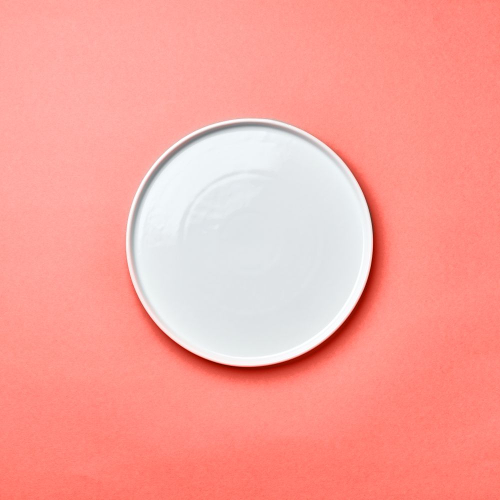 Decorative ceramic handmade empty white plate presented on a background in color of the year 2019 Living Coral pantone with copy space for your menu. Can be used for montage your products. Top view.. Porcelain empty round handmade a plate on a background in color of the year 2019 Living Coral pantone with a copy of space. Flat lay