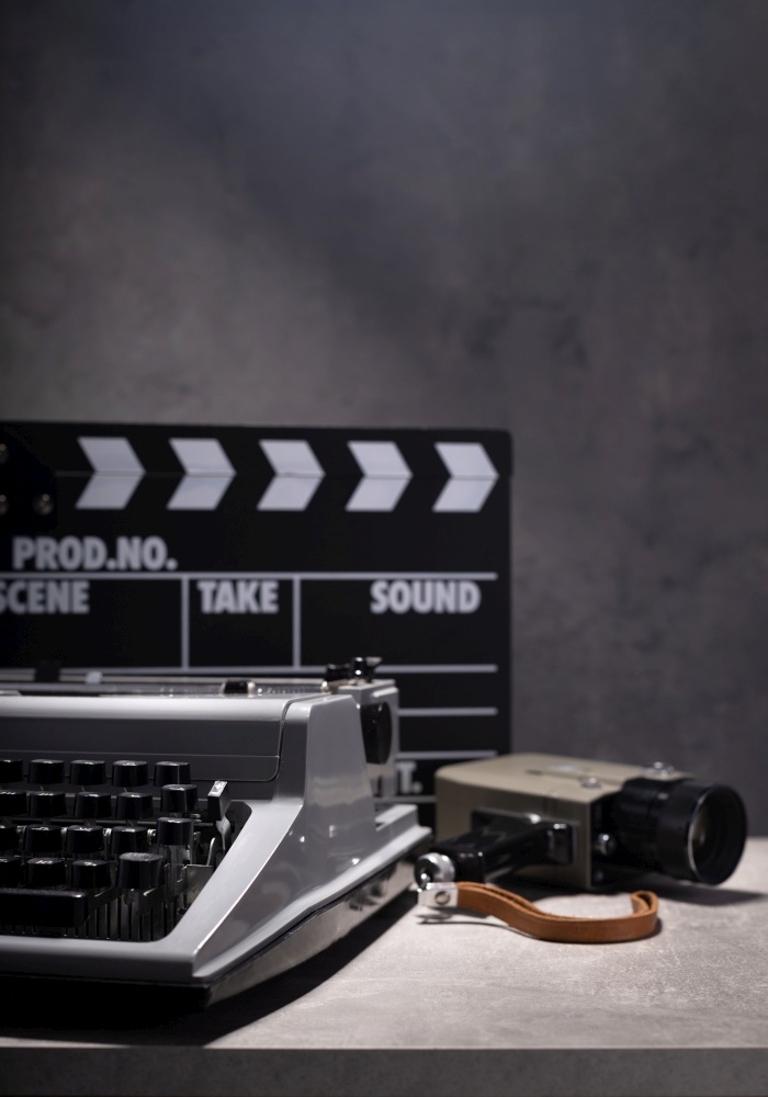 vintage retro typewriter, film camera and movie clapper board at table near wall background, abstract retro writer concept