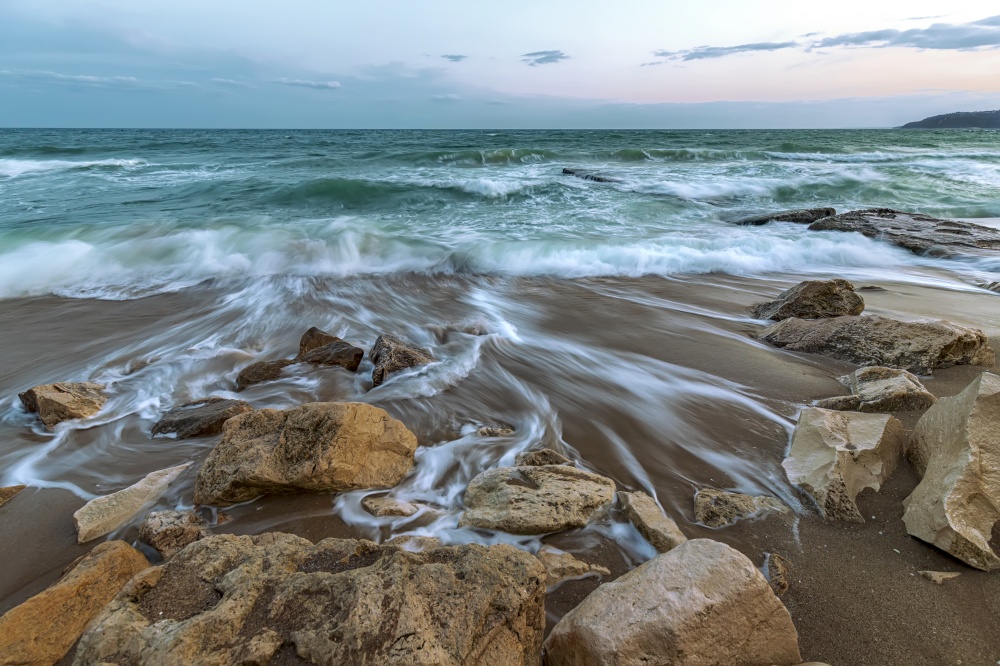 Stunning long exposure seascape with waves flowing between rocks.