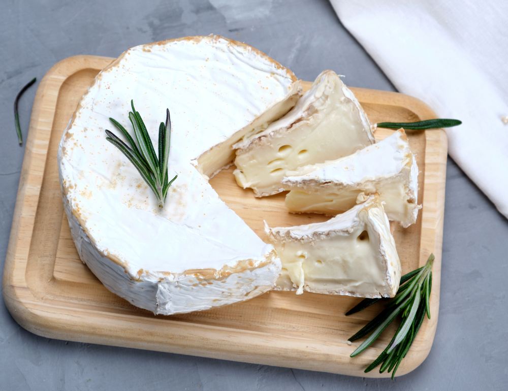 round brie cheese on a wooden board, gray background , top view