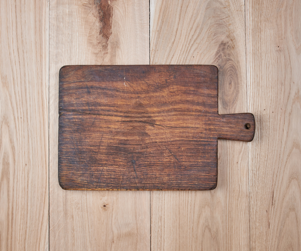 empty old kitchen cutting board on a wooden table, top view, top view