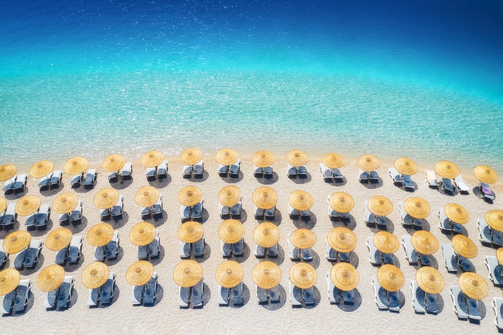 Aerial view of sea, empty sandy beach with sunbeds and umbrellas at sunny day in summer. Blue lagoon in Oludeniz, Turkey. Tropical landscape with clear turquoise water, deck chairs. Travel and leisure