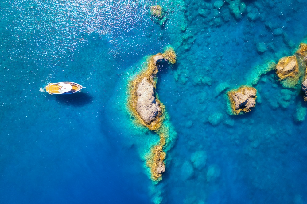 Speed boat on blue sea at sunrise in summer. Aerial view of motorboat on sea bay, rocks in clear azure water. Tropical landscape with yacht, stones. Top view from drone. Travel in Oludeniz, Turkey
