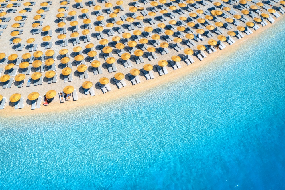 Aerial view of sea, empty sandy beach with sun beds and umbrellas at sunset in summer. Blue lagoon in Oludeniz, Turkey. Tropical landscape with clear turquoise water, deck chair. Travel and nature