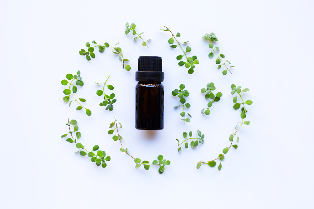Top view. Bottle of essential oil with marjoram on white background.