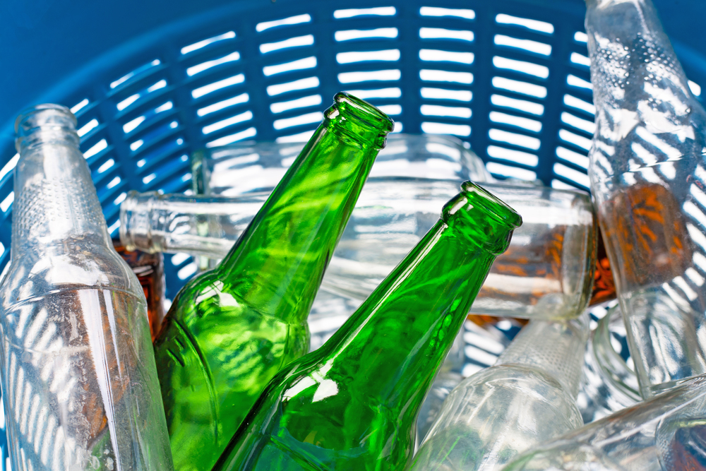 Glass bottles in blue waste basket.