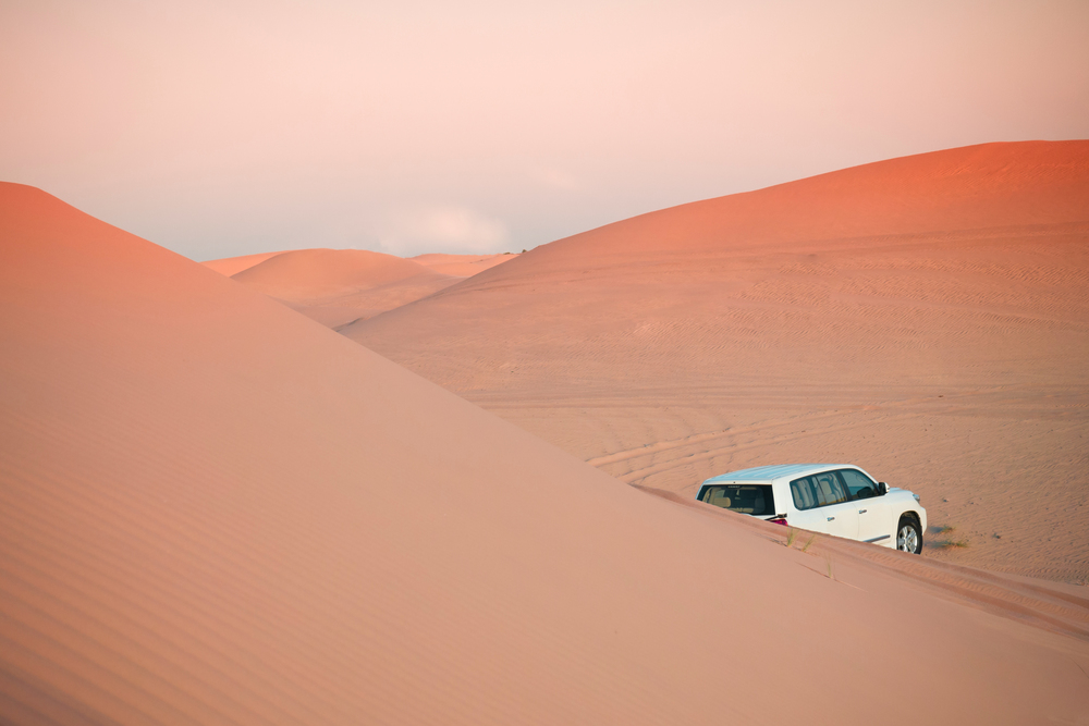 Desert offroad Sunset Safari in the Dubai - Abu Dhabi. SUV car in Al Wathba dessert among exotic sand dunes under evening light
