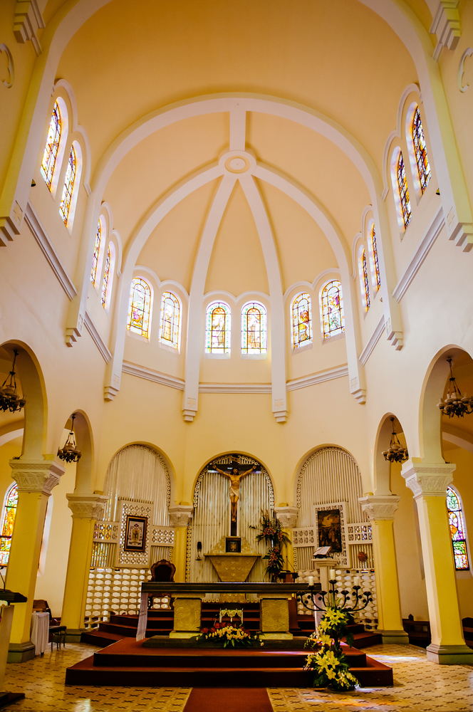 FEB 26, 2014 Dalat, Vietnam - Da Lat Cathedral high ceiling arch shape yellow prayer hall with old  altar and Jesus Christ statue and stainglass