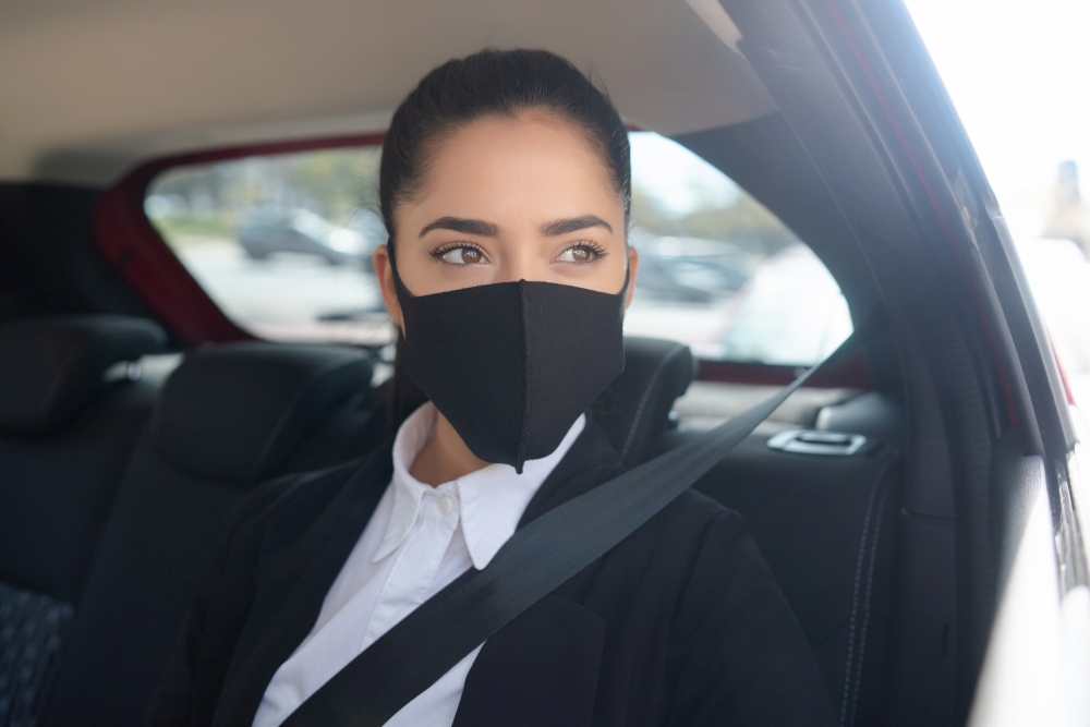 Portrait of young business woman wearing face mask on her way to work in a cab. Business concept. New normal lifestyle concept.