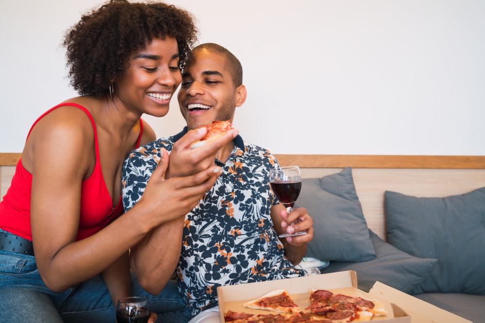 Portrait of happy young latin couple having dinner together and drinking wine at their home. Lifestyle and relationship concept.