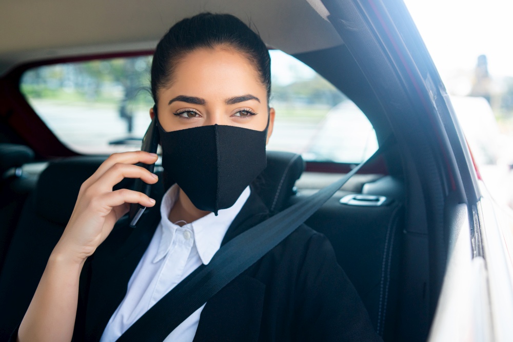Portrait of business woman wearing face mask and talking on the phone on her way to work in a car. Business concept. New normal lifestyle concept.