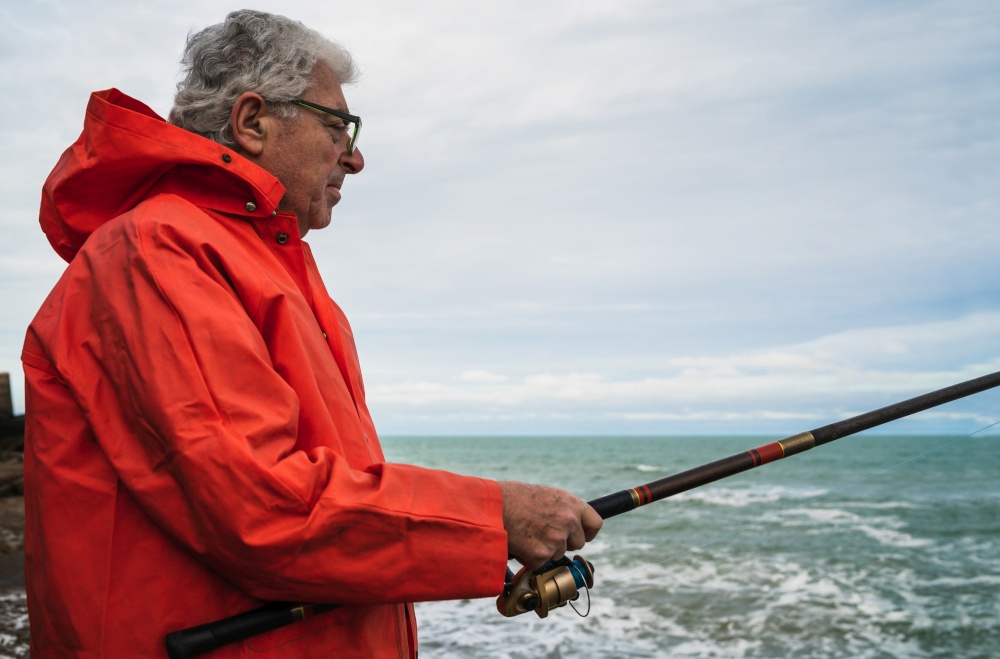 Portrait of an senior man fishing in the sea, enjoying life.  Fishing and sport concept.