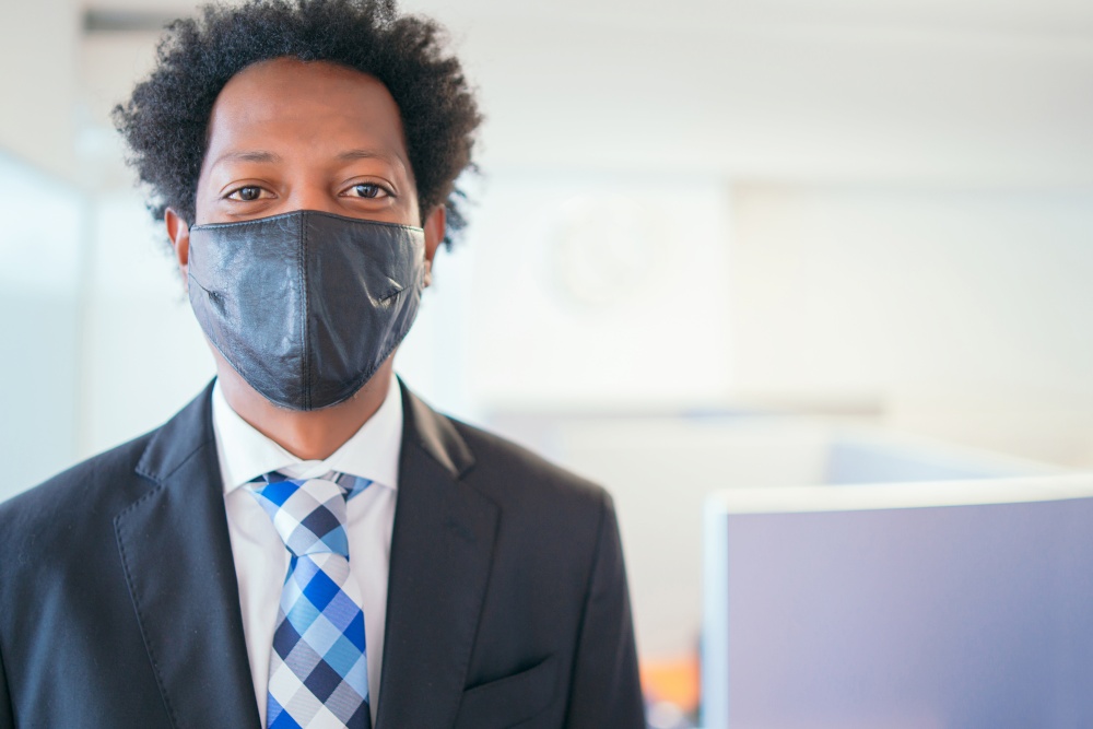 Portrait of professional businessman wearing face mask while standing at modern office. New normal lifestyle. Business concept.