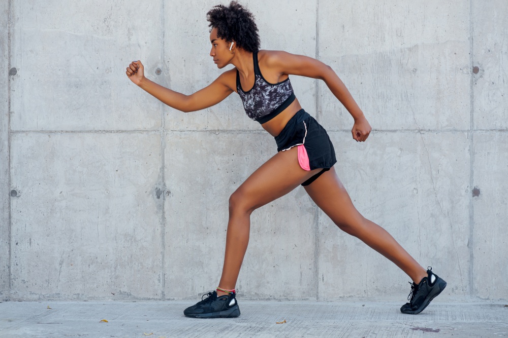 Afro athletic woman running and doing exercise outdoors. Sport and healthy lifestyle concept.