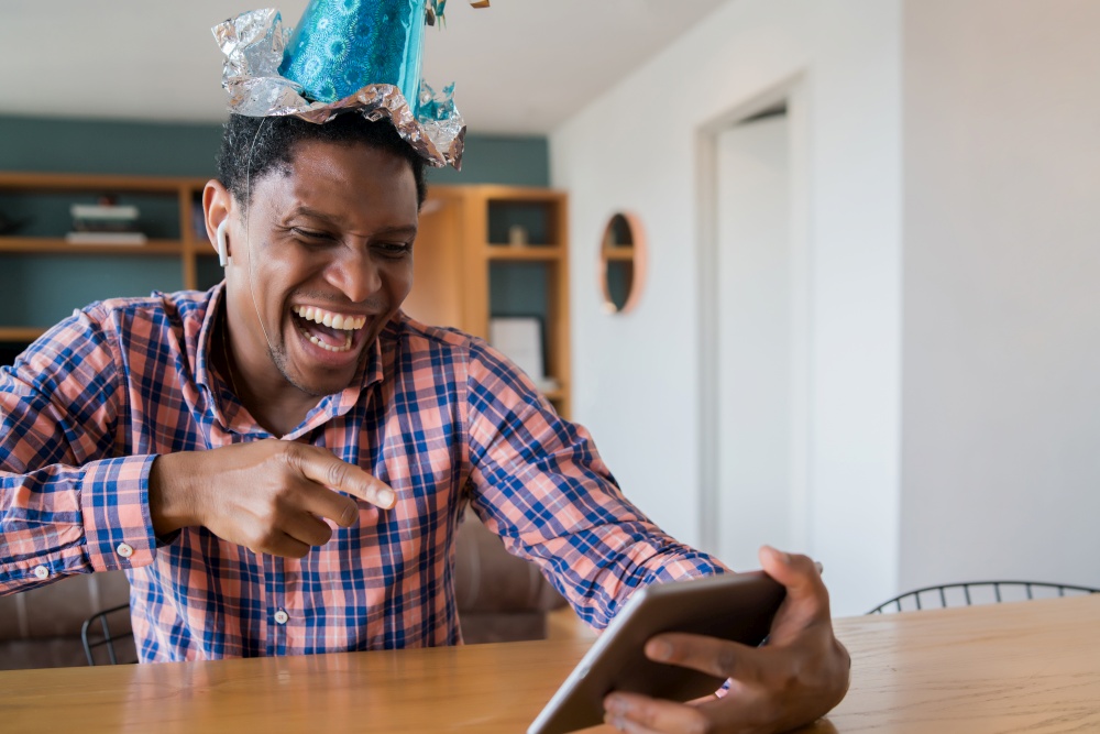 Portrait of man celebrating birthday on a video call with digital tablet at home.New normal lifestyle concept.