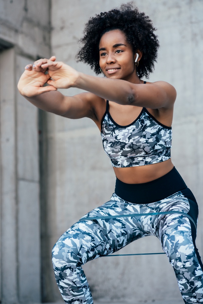 Afro athletic woman exercising and doing squat leg outdoors. Sport and healthy lifestyle concept.