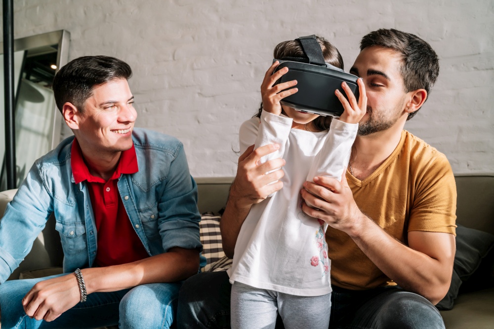 Gay couple and their kids playing video games with VR glasses together at home. Family concept.