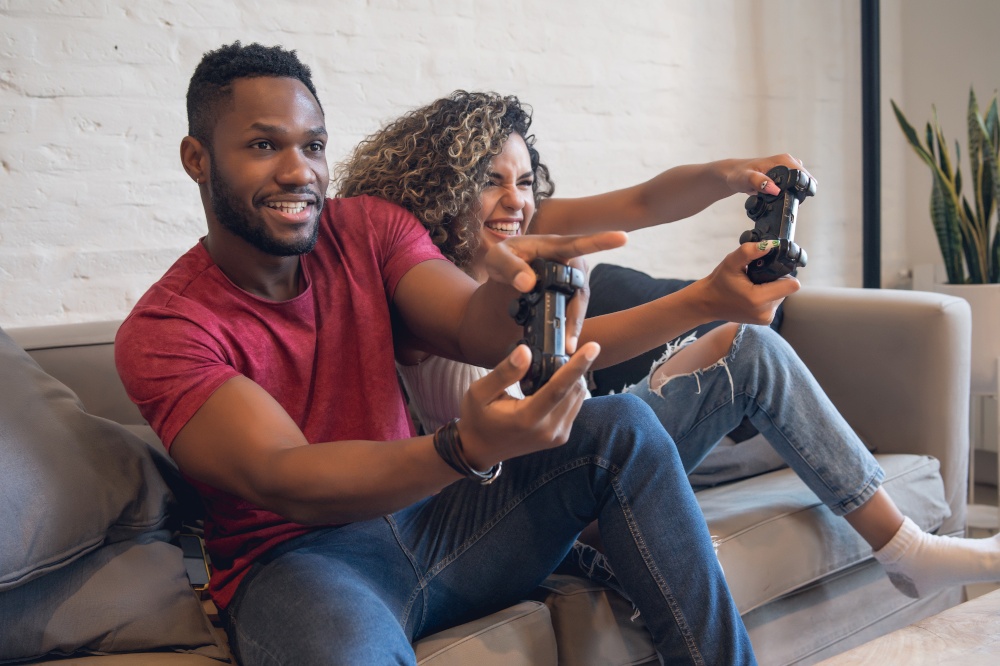 Young couple having fun while playing video games together at home.