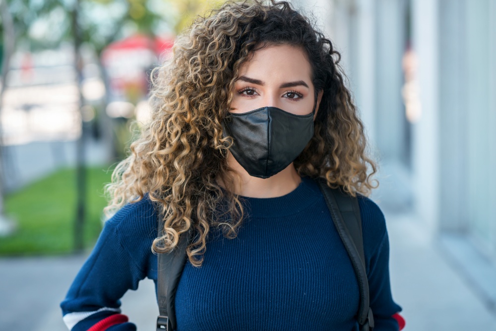 Latin woman wearing a face mask while standing outdoors on the street. Urban concept. New normal lifestyle concept.